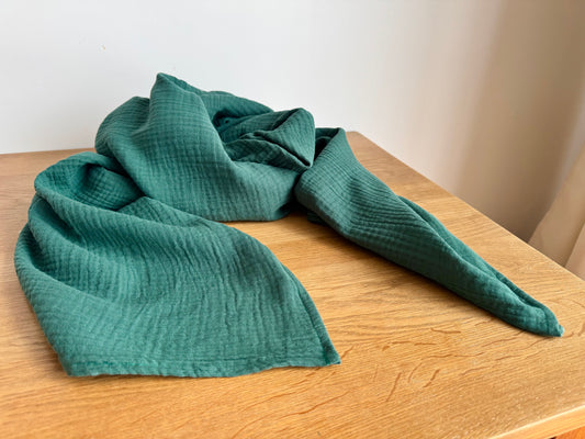 emerald Green muslin cotton scarf wrap on a wooden surface with a plain background