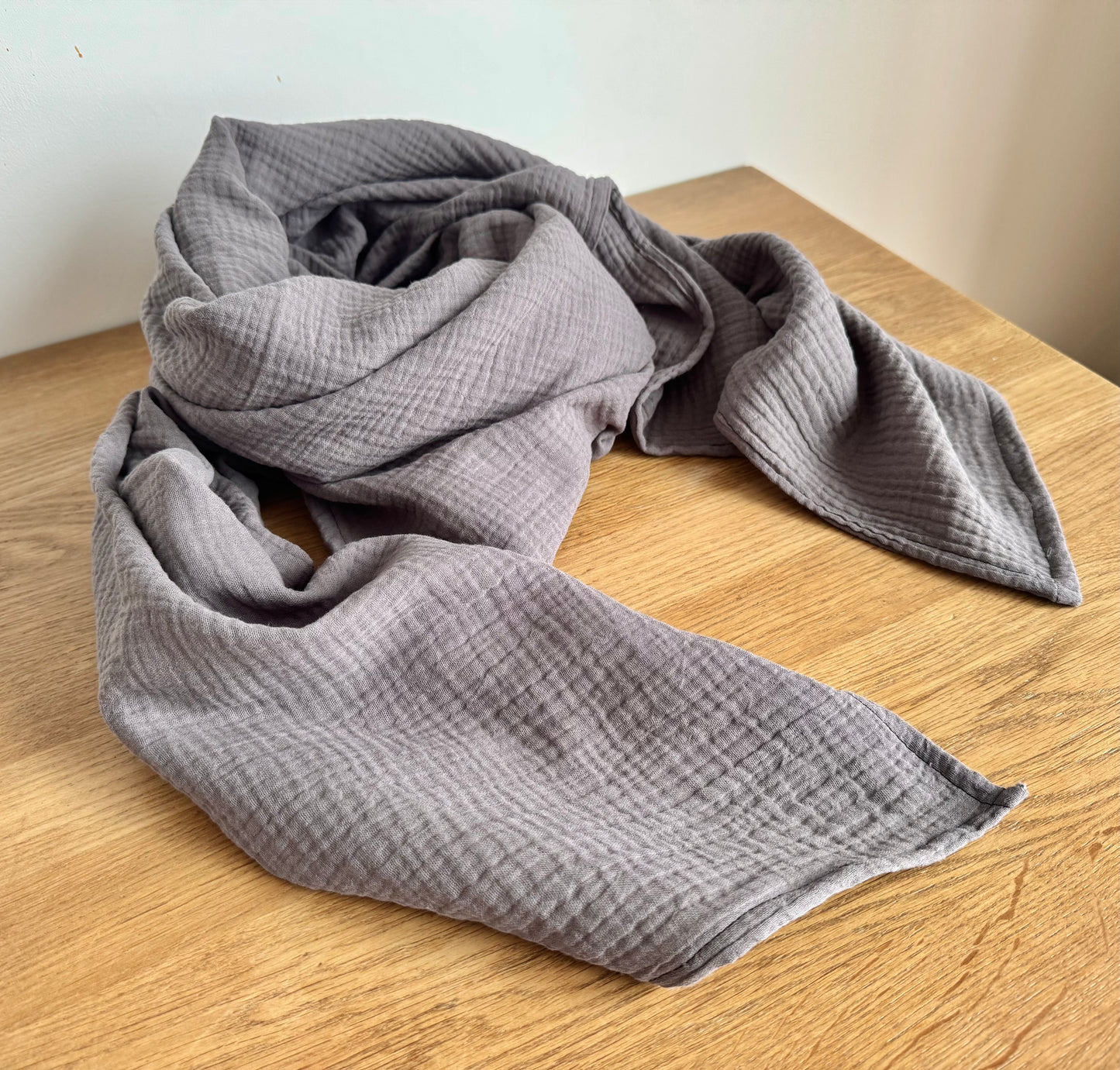 graphite Gray muslin cotton scarf wrap blanket on a wooden surface